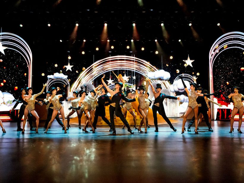 Blinded by Delight Bühnenszene mit vielen Tänzerinnen und Sternen im Hintergrund