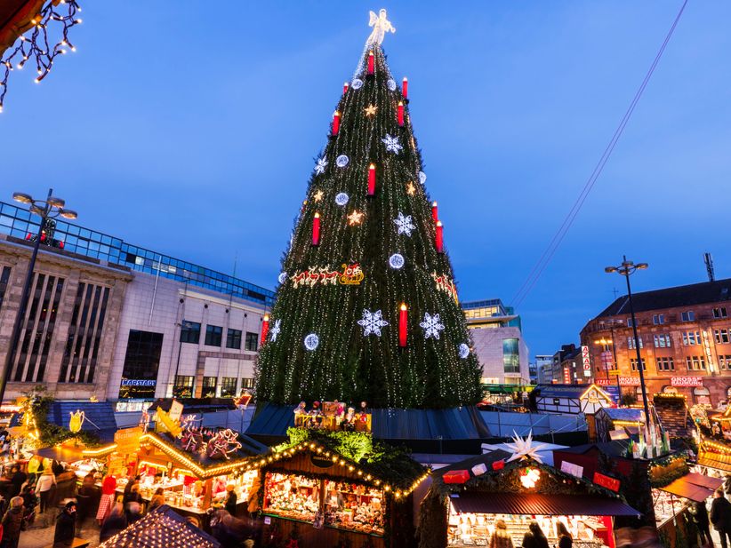 Großer Weihnachtsbaum mit Lichtern auf dem Dortmunder Weihnachtsmarkt, umgeben von Ständen.
