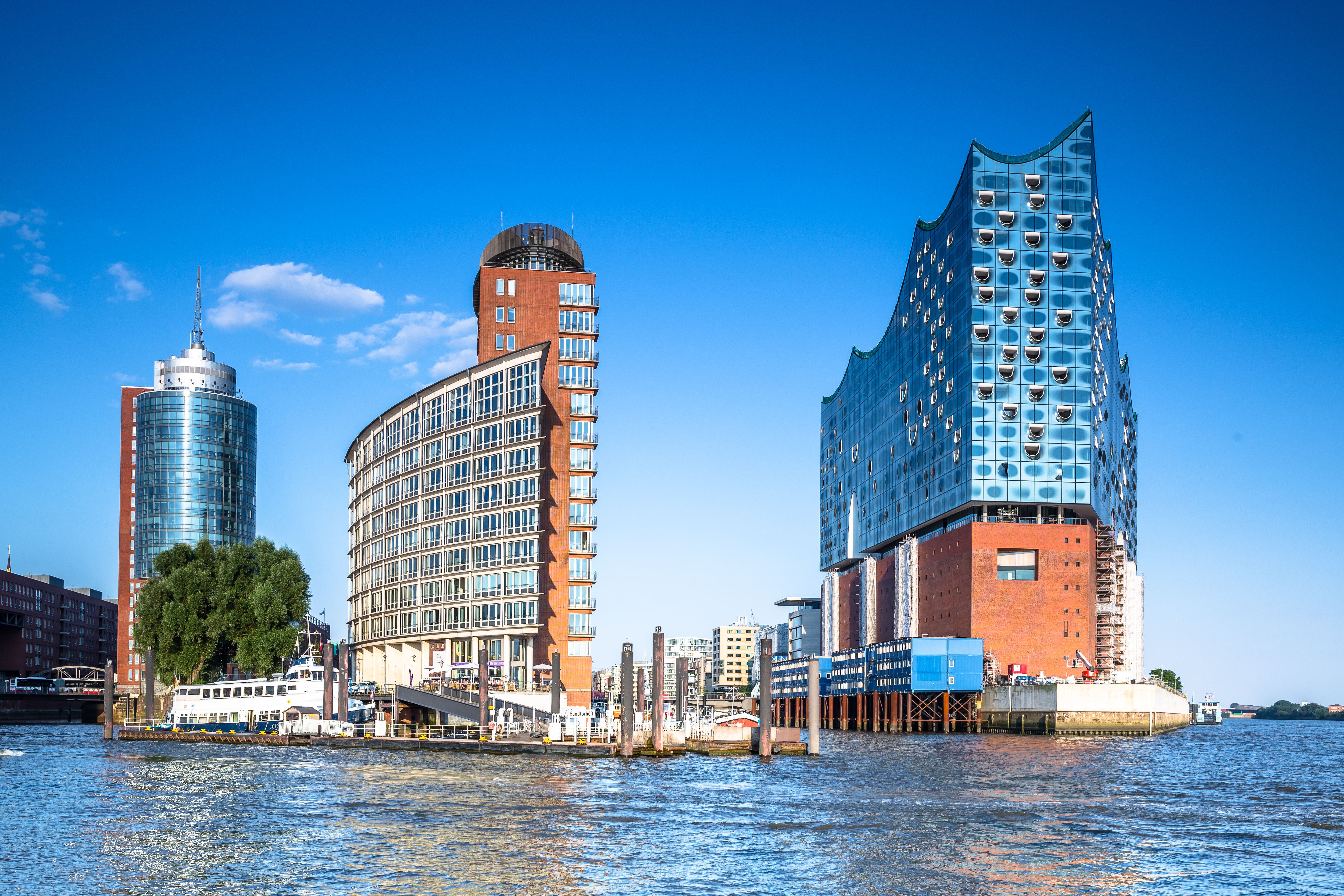 Elbphilharmonie und zwei andere Gebäude von vorne bei blauem Himmel