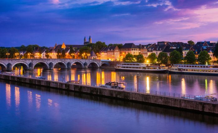 Beleuchtetes Panorama der Stadt Maastricht an der Maas in der Abenddämmerung