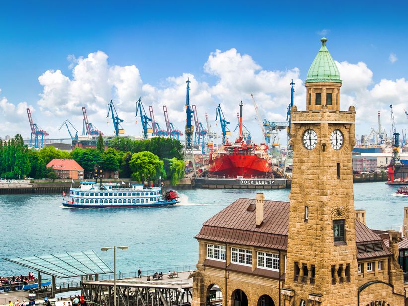 Pegelturm am Hamburger Hafen mit Schiff und Ladekränen im Hintergrund