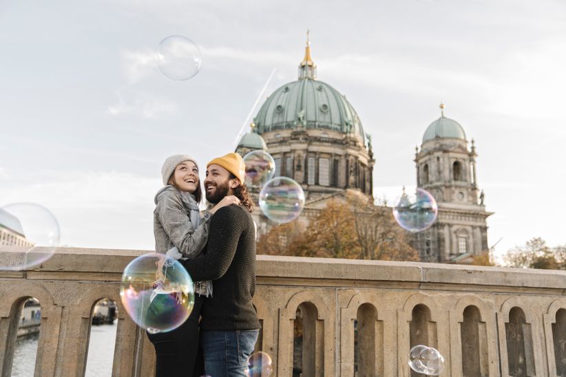 Junges Paar umarmt sich und schaut Seifenblasen in Berlin an