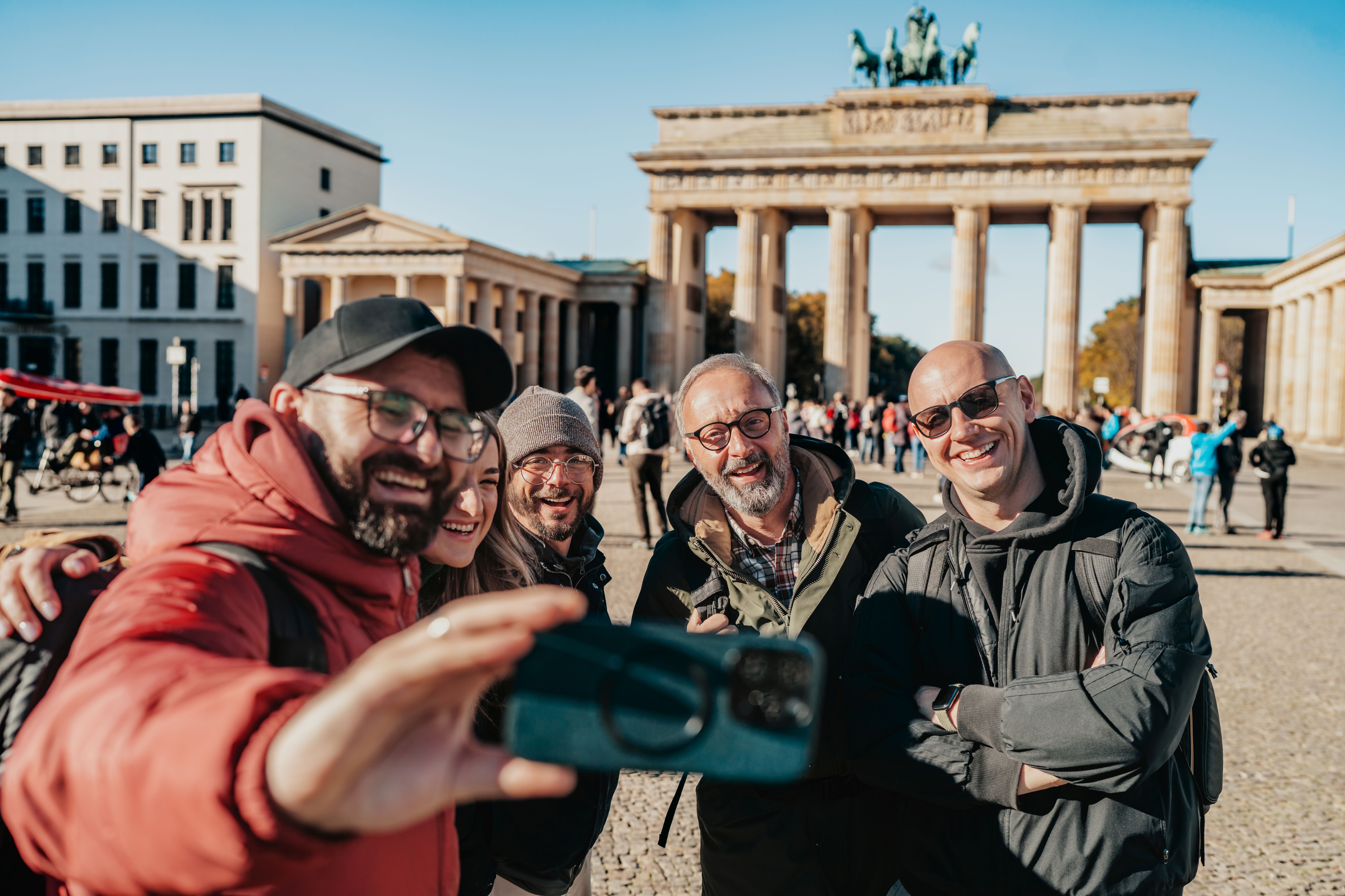 Reisegruppe schießt vor dem Brandenburger Tor in Berlin ein Selfie