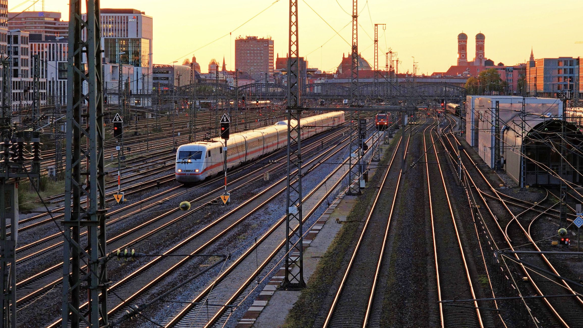 Blick auf die Schienen und einen einfahrenden ICE bei Sonnenuntergang.
