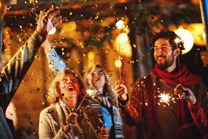 Menschen feiern Silvester mit Wunderkerzen im Freien bei Nacht