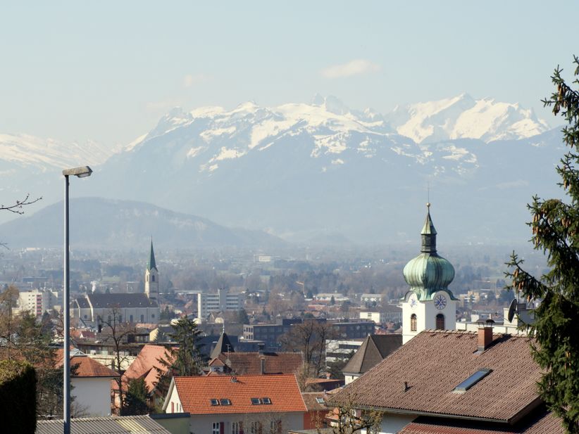 Im Vordergrund Dächer von Dornbirn und im Hintergrund Berge, die zum Teil mit Schnee bedeckt sind