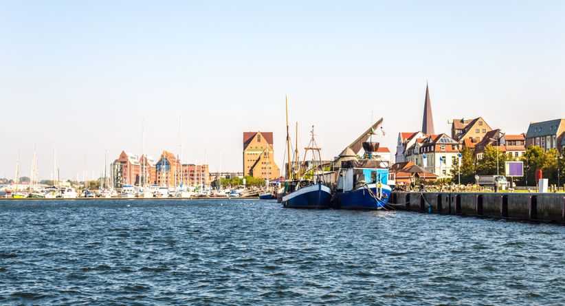 Hafen von Rostock mit festgemachten Booten und Blick auf das offene Wasser der Ostsee.