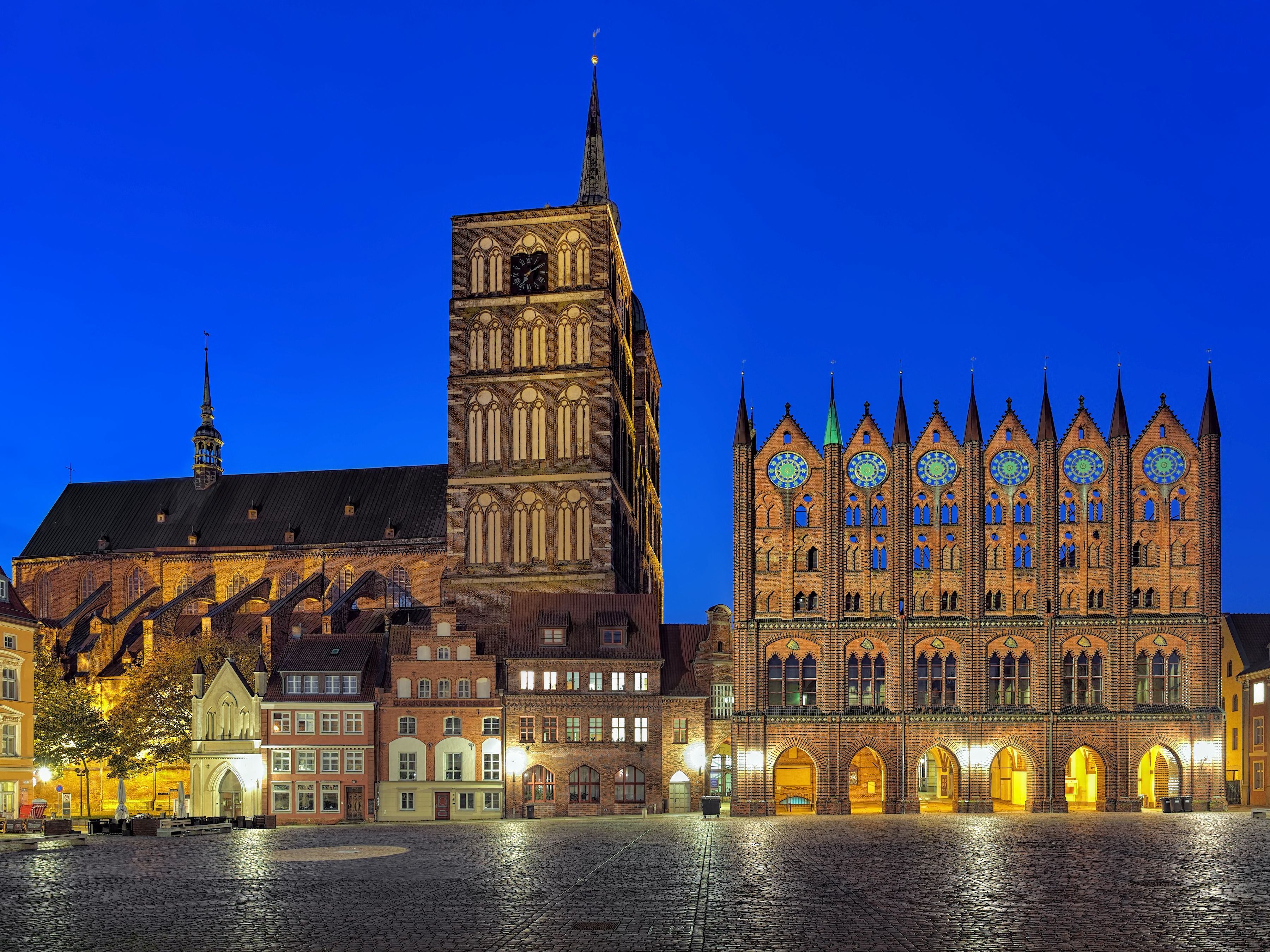 Das gotische Rathaus von Stralsund am Abend, stimmungsvoll beleuchtet mit eindrucksvoller Backsteinfassade.