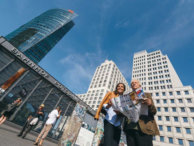 Paar mittleren Alters mit Stadtplan vor Bahnhof Potsdamer Platz in Berlin