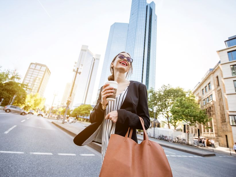 Geschäftsfrau auf einer Straße in Frankfurt mit Hochhaus im Hintergrund
