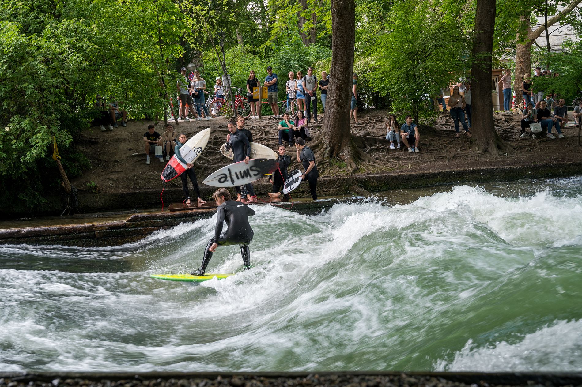 Surfer auf der Eisbachwelle am Rande des Englischen Gartens in München während einer geführten Fahrradtour.