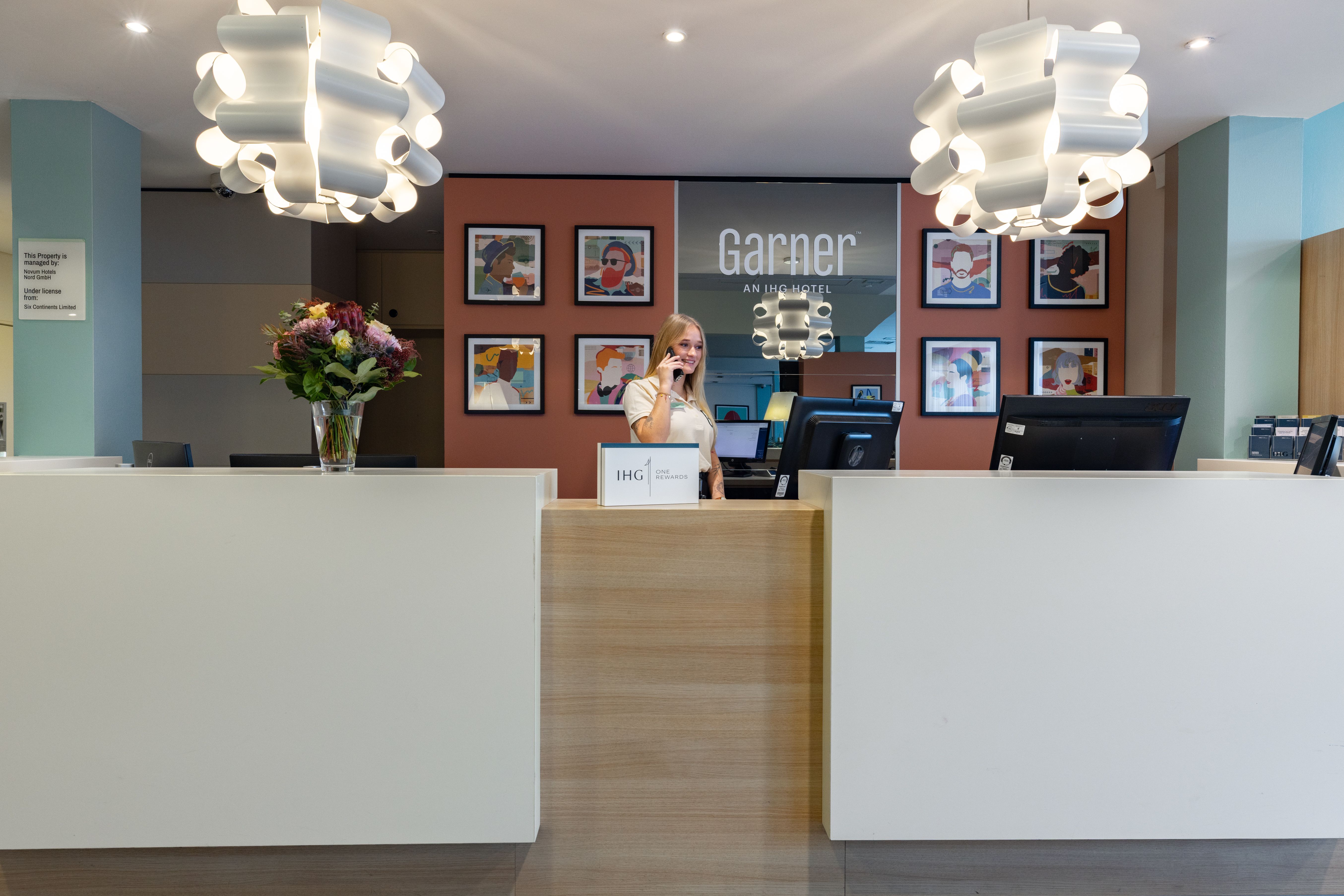 Rezeptionstheke mit großen futuristischen Lampen und Mitarbeiterin am Telefon hinter der Theke.