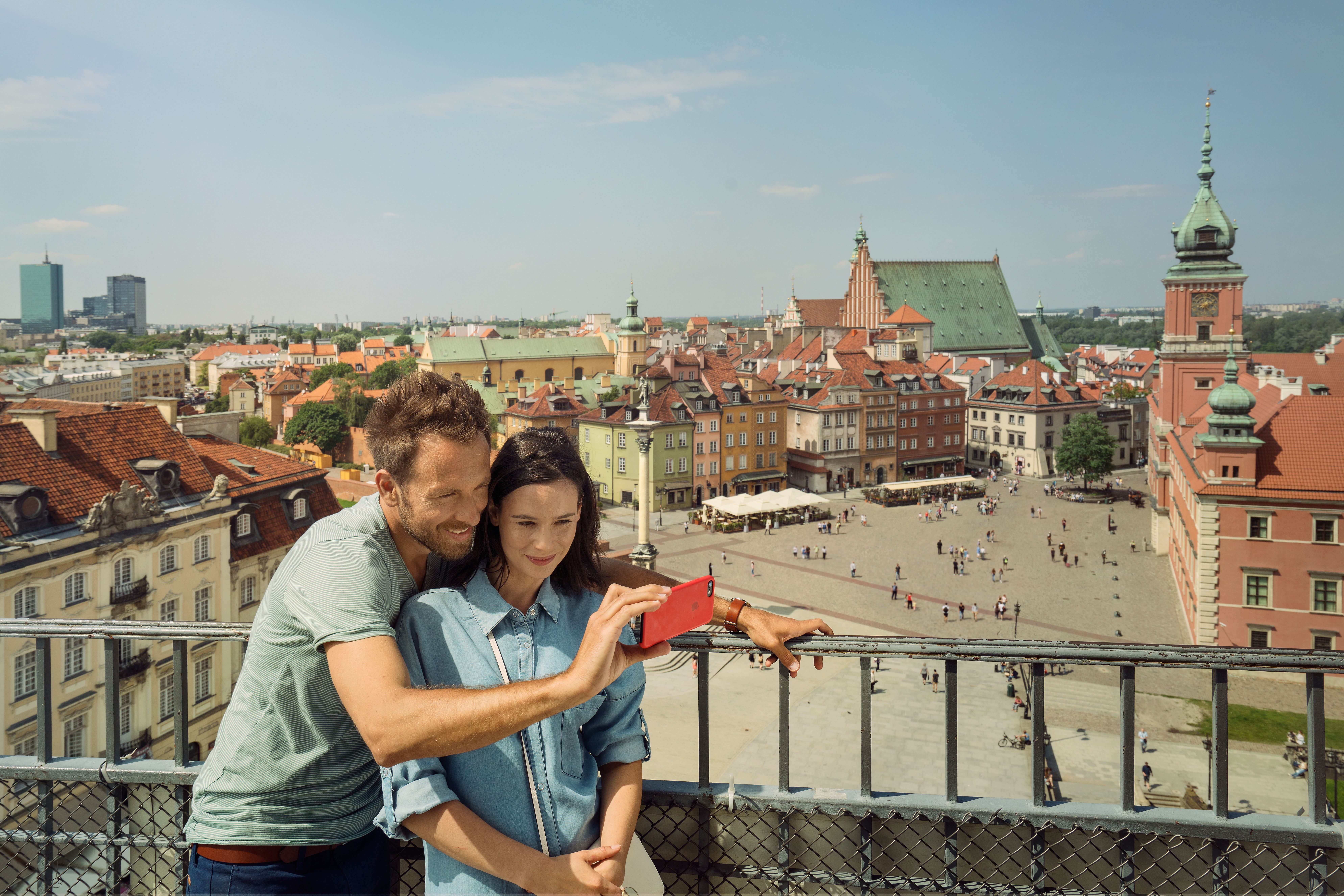 Ein Paar macht ein Selfie auf dem Schlossplatz in Warschau mit dem Königsschloss im Hintergrund.