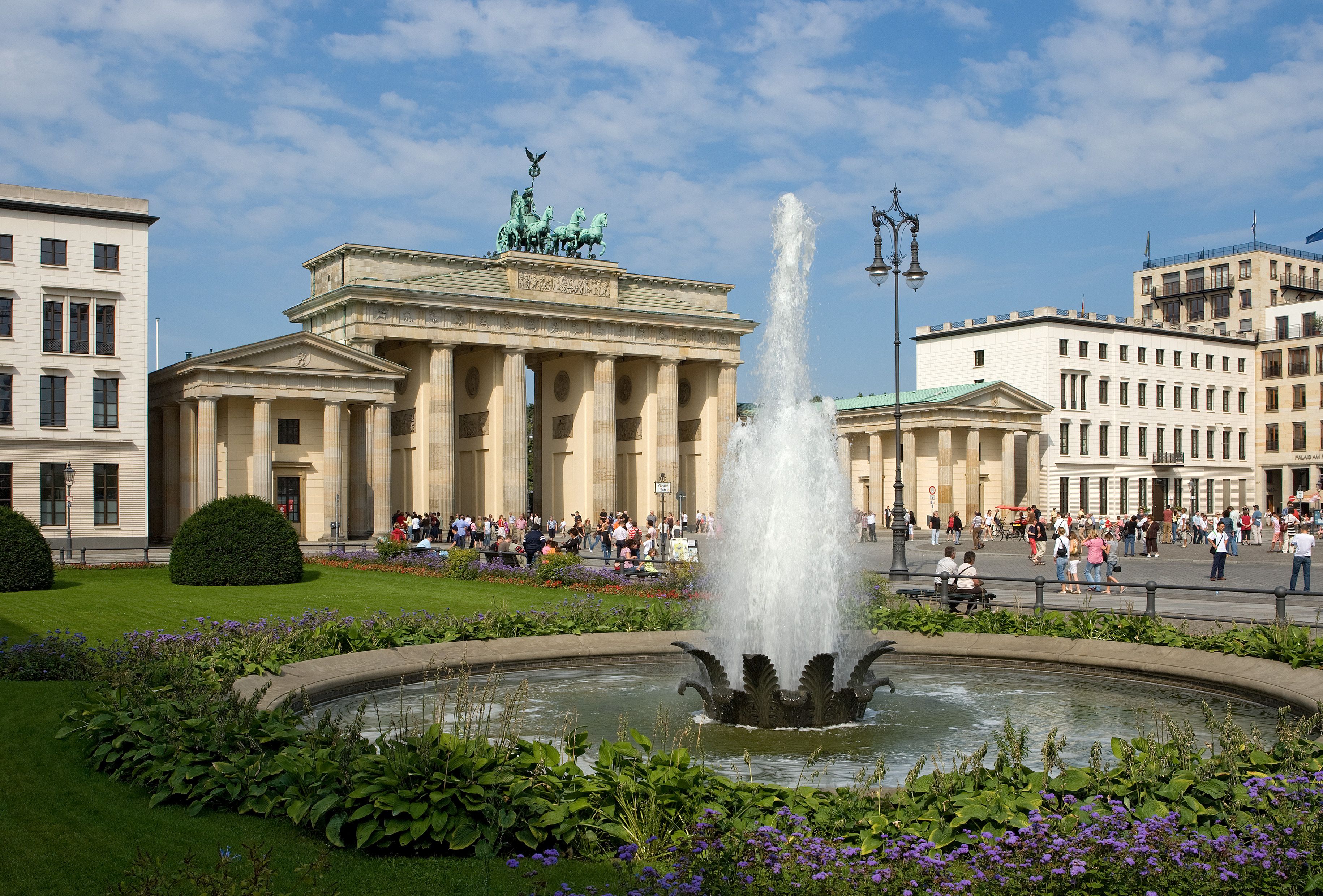 Blick auf das Brandenburger Tor und eine Wasserfontäne mit Blumenbeet
