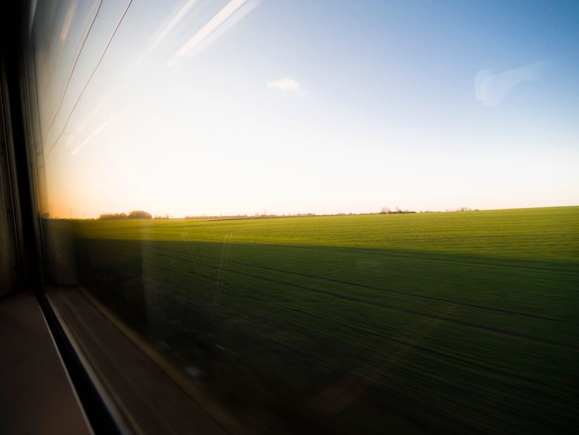 Blick aus dem ICE-Fenster auf grüne Felder