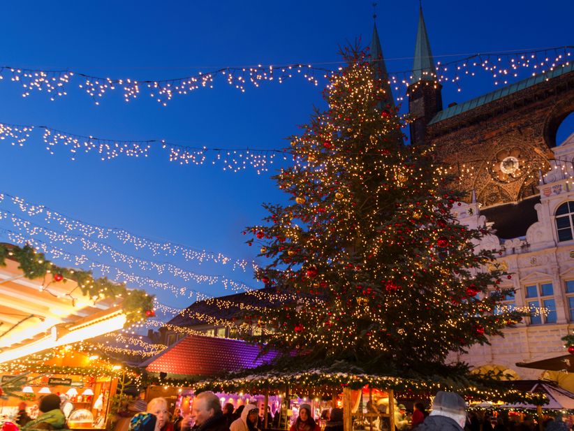 Weihnachtsmarkt in Lübeck mit beleuchteten Ständen und historischen Gebäuden im Hintergrund
