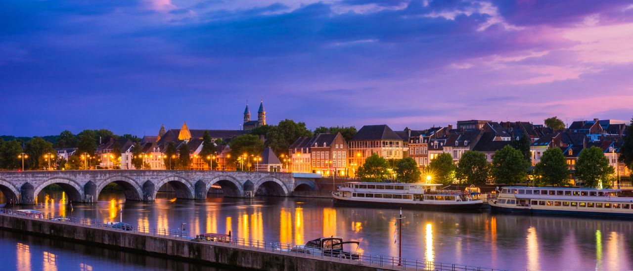 Beleuchtetes Panorama der Stadt Maastricht an der Maas in der Abenddämmerung