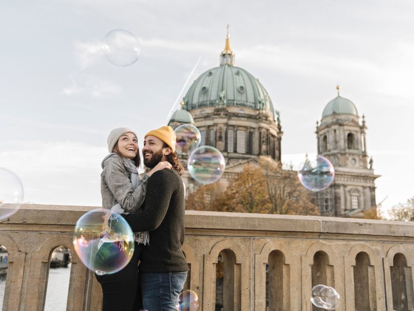 Junges Paar umarmt sich und schaut Seifenblasen in Berlin an
