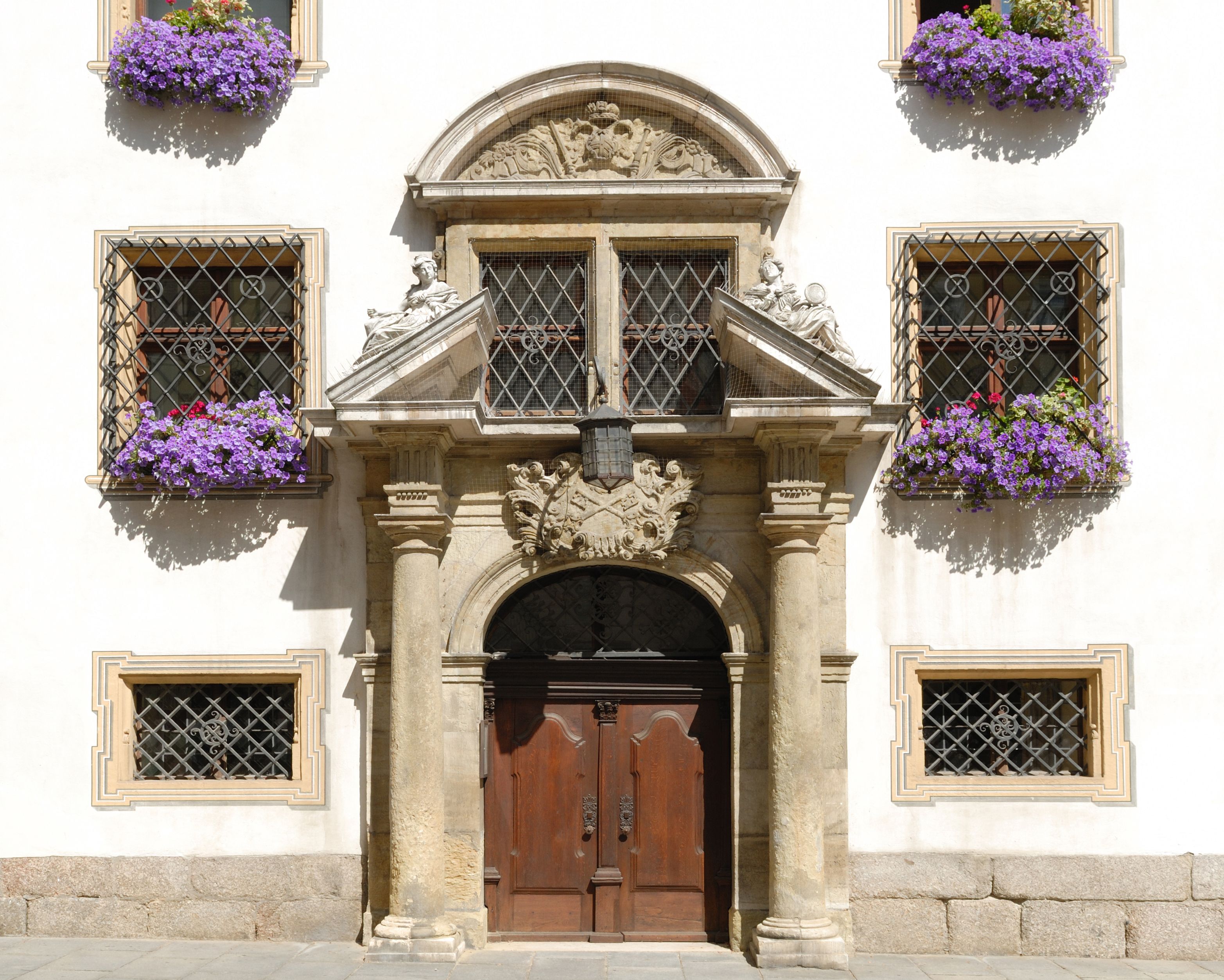 Dekorative Haustür in Regensburg, umrahmt von blühenden Blumen und historischen Fassadendetails.