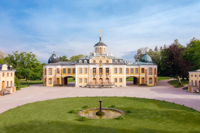 Frontale Ansicht des barocken Schlosses Belvedere bei Weimar mit seiner geschwungenen Fassade, verzierten Eingangspartie und vorgelagertem Ehrenhof, eingerahmt von symmetrisch angelegten Gartenflächen.