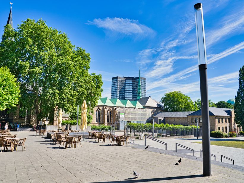 Stühle und Tische auf einem Platz vor dem Essener Dom bei Sonne