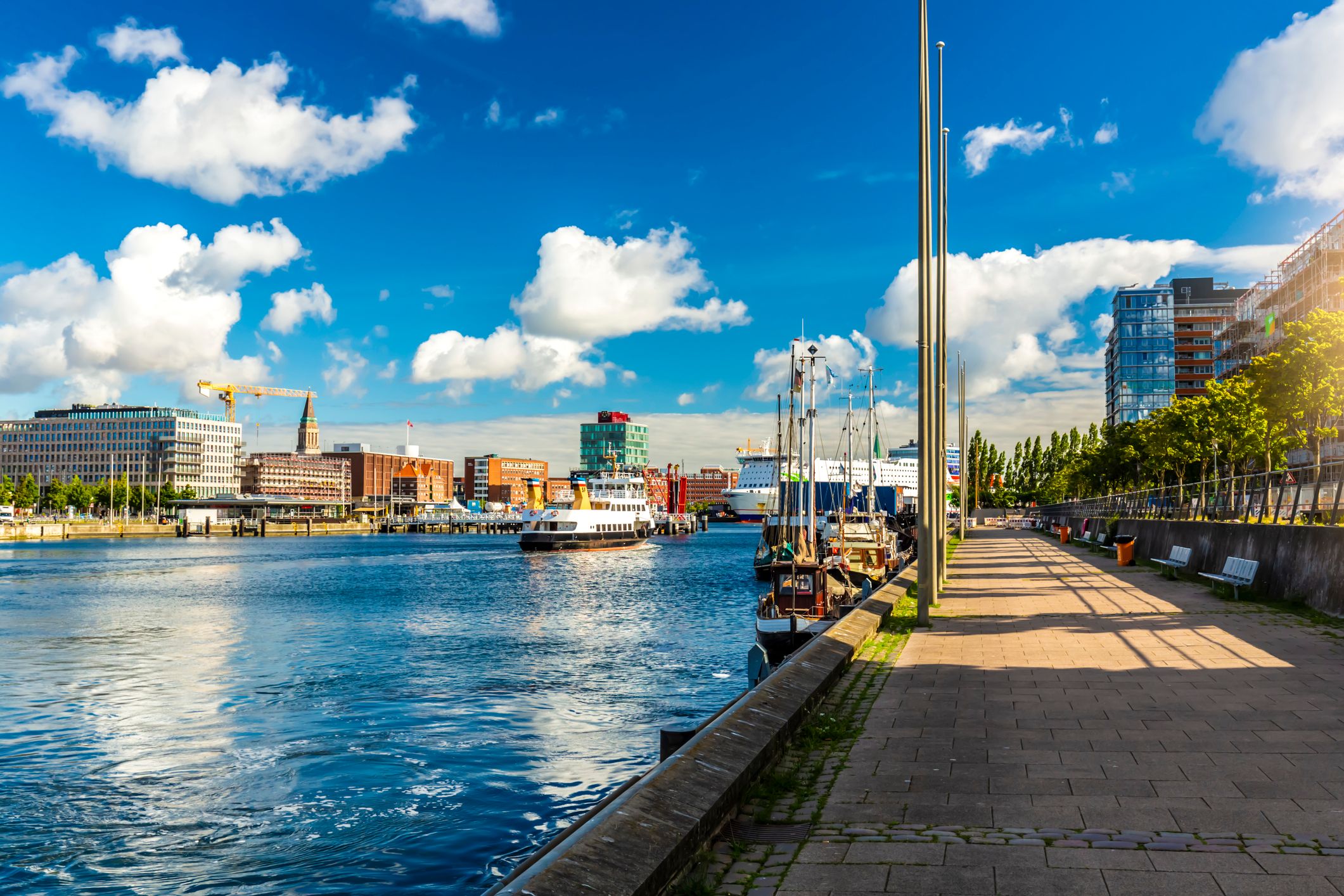 Spazierweg entlang der Kieler Hafenpromenade mit Blick auf die Ostsee und ein vorbeifahrendes Schiff – maritimes Flair zwischen Stadt und Wasser.