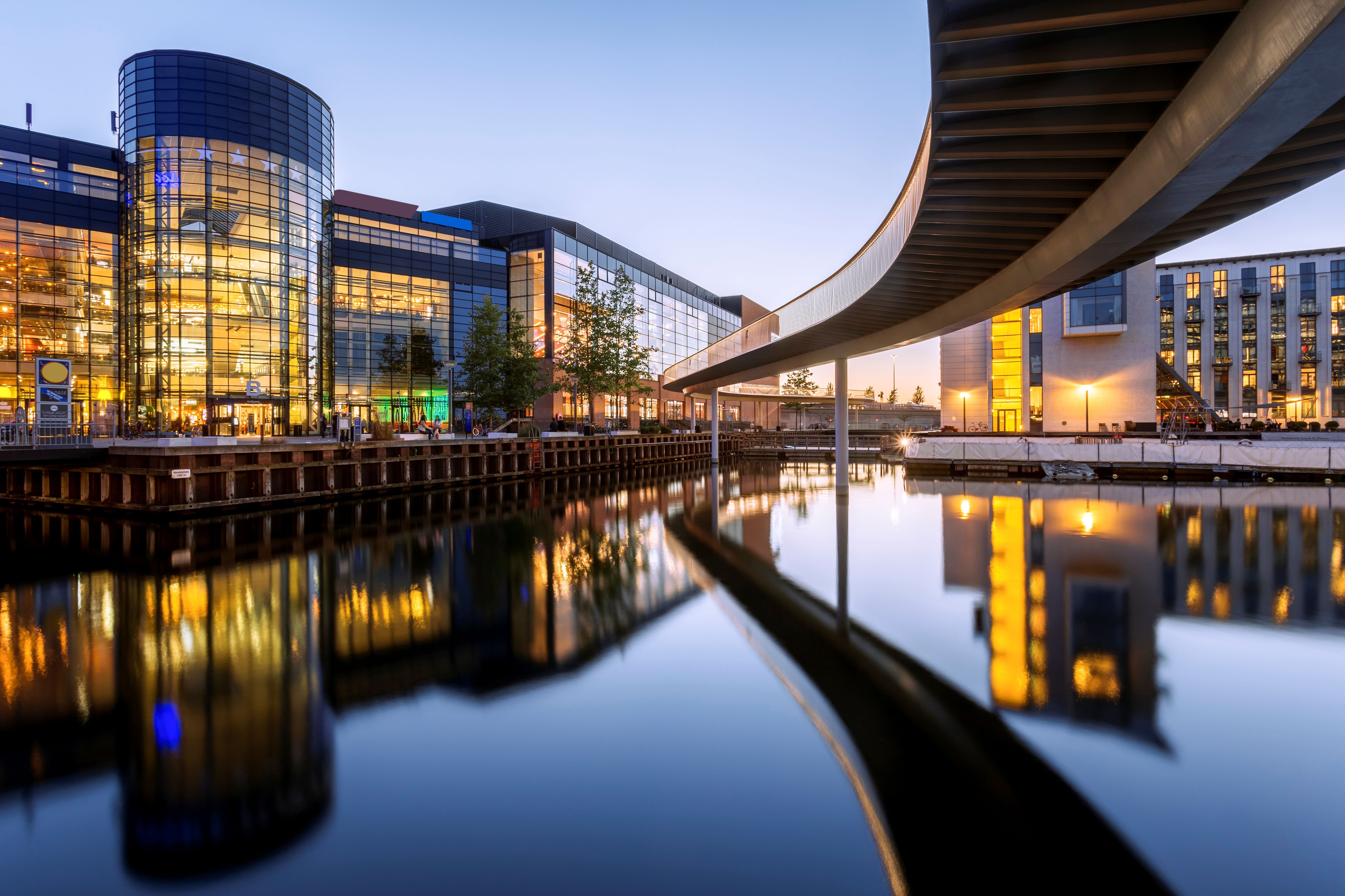 Blick auf die Fahrradbrücke - auch Fahrradschlange genannt - und den Öresund in Kopenhagen mit beleuchteten Bürogebäuden im Hintergrund