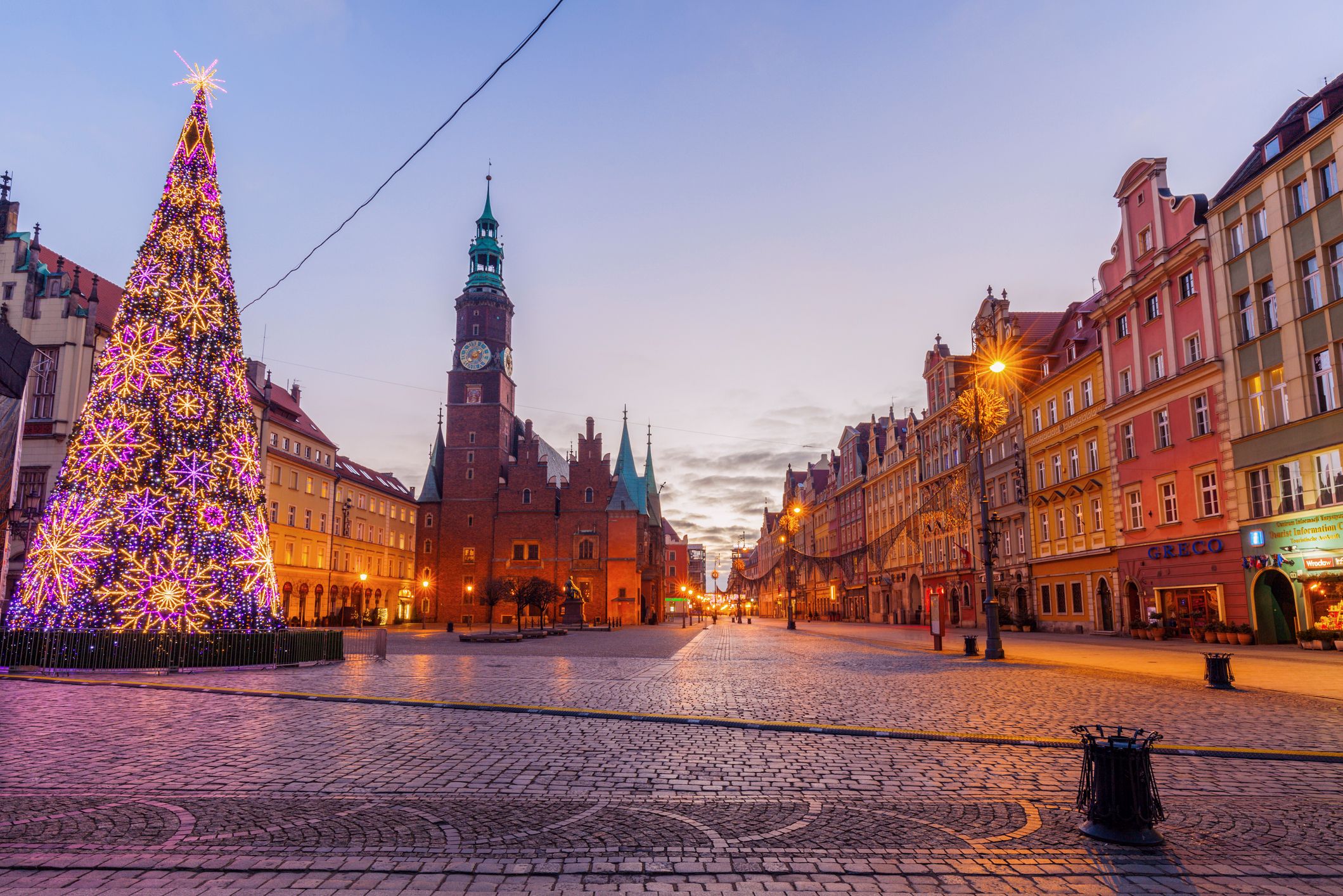 Beleuchteter Marktplatz in Breslau während der Weihnachtszeit, geschmückt mit einem großen Weihnachtsbaum und dem historischen Rathaus im Hintergrund