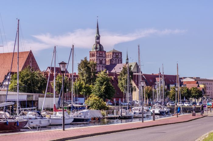 Segelboote liegen im Hafen von Stralsund vor historischer Kulisse mit Backsteingebäuden und Blick auf das ruhige Wasser der Ostsee.