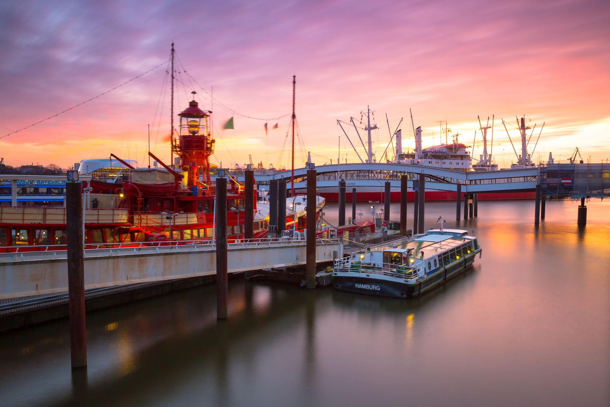 Hamburger Hafen bei rosanem Himmel am Abend und Stegen und Booten