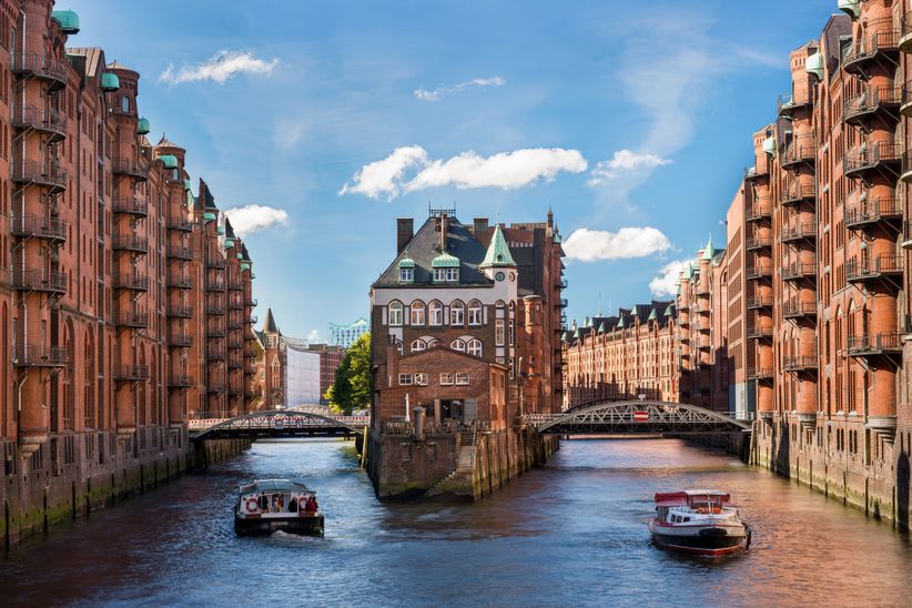 Speicherstadt in Hamburg mit zwei Booten auf zwei Kanälen um ein Gebäude herum