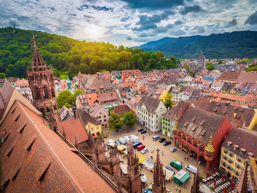 Blick auf Dach des Münster, Markt und Kaufhaus in Freiburg mit grünen Bergen im Hintergrund