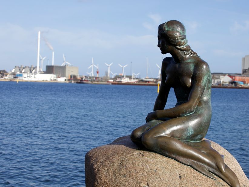 Statur der kleinen Meerjungfrau auf einem Stein sitzend mit dem Kanal im Hintergrund in Kopenhagen