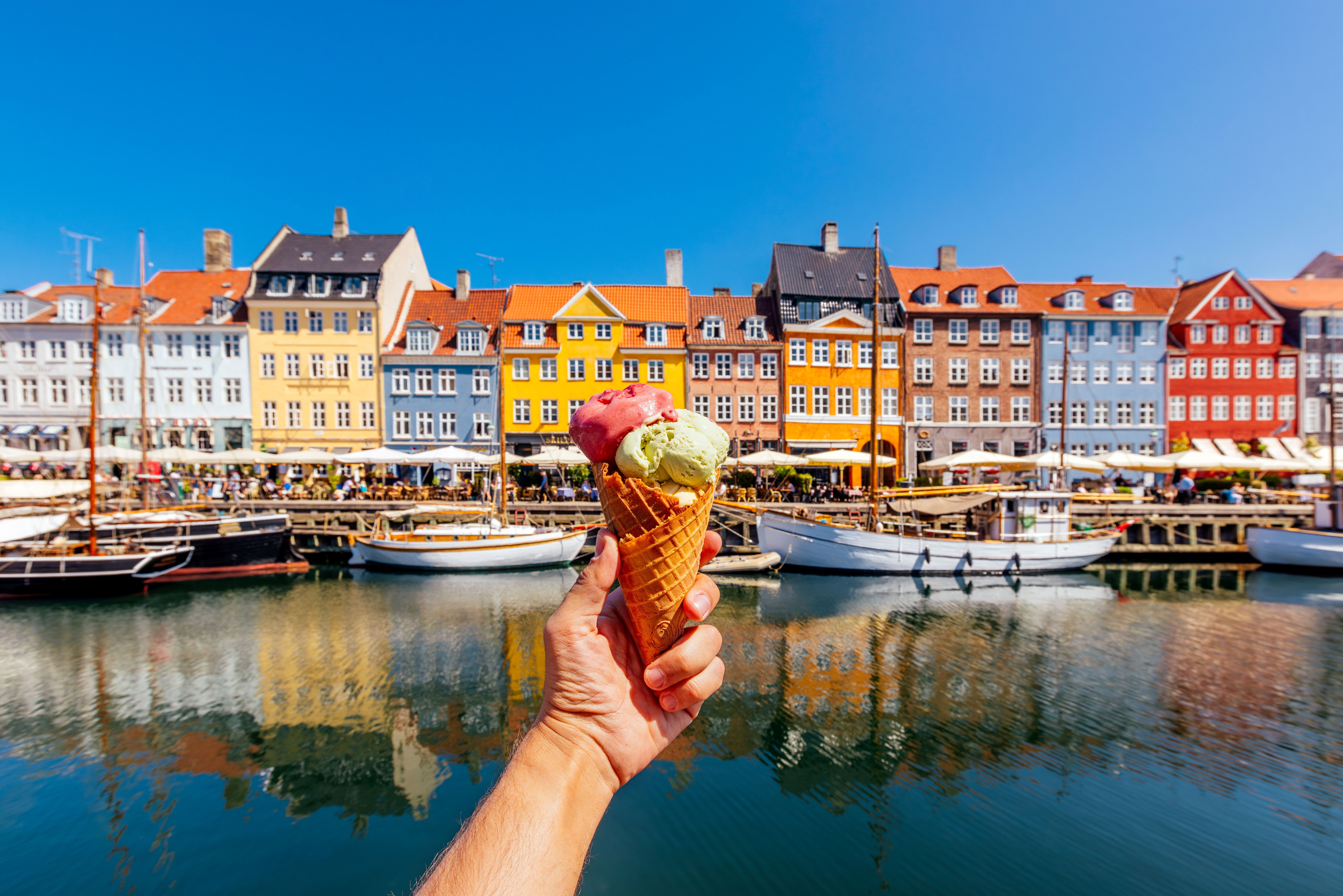 Hand hält ein Eis vor einem Hafenpanorama in Kopenhagen