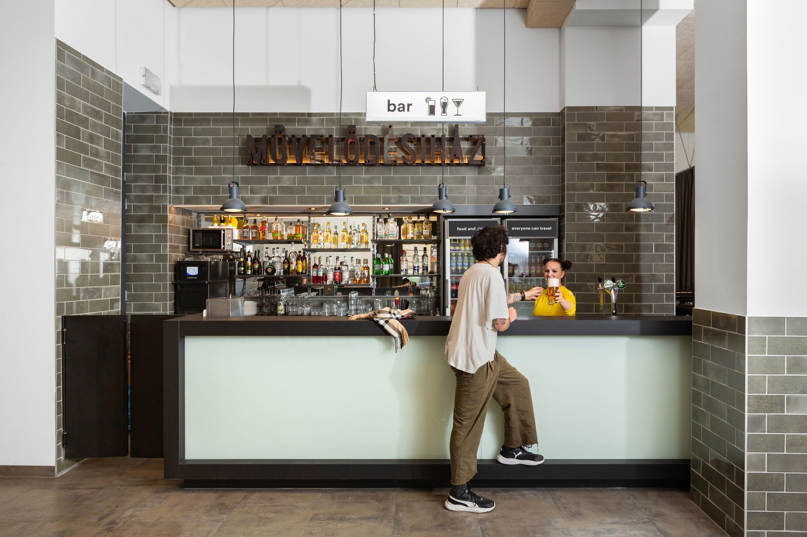 Junger Mann bestellt Getränk an der Bar im a&o Hostel Budapest