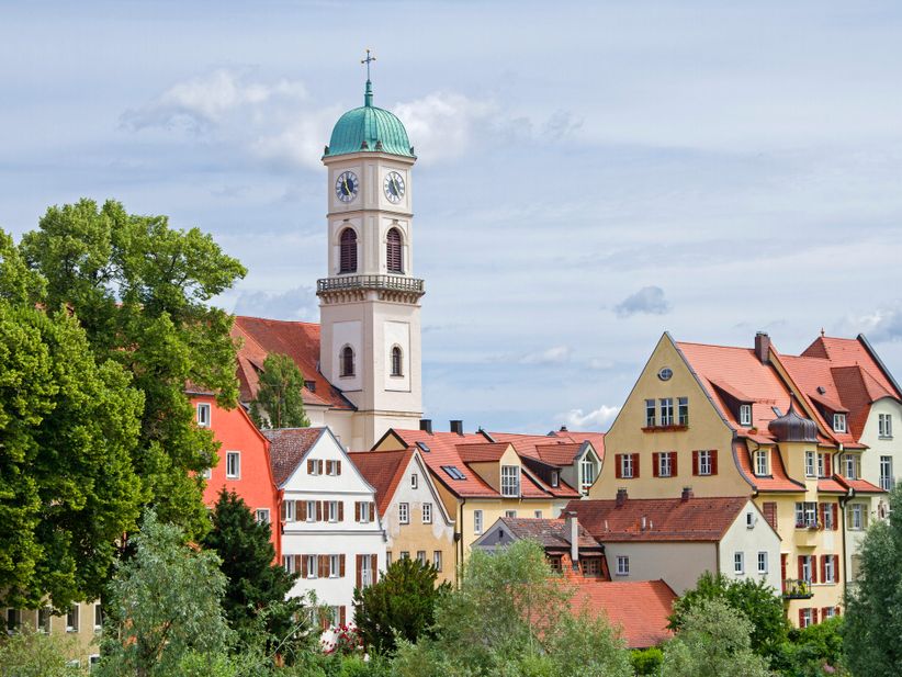 Panoramablick aus der Entfernung auf die Altstadt von Regensburg mit markanten Kirchtürmen, historischen Gebäuden und der Donau im Vordergrund.