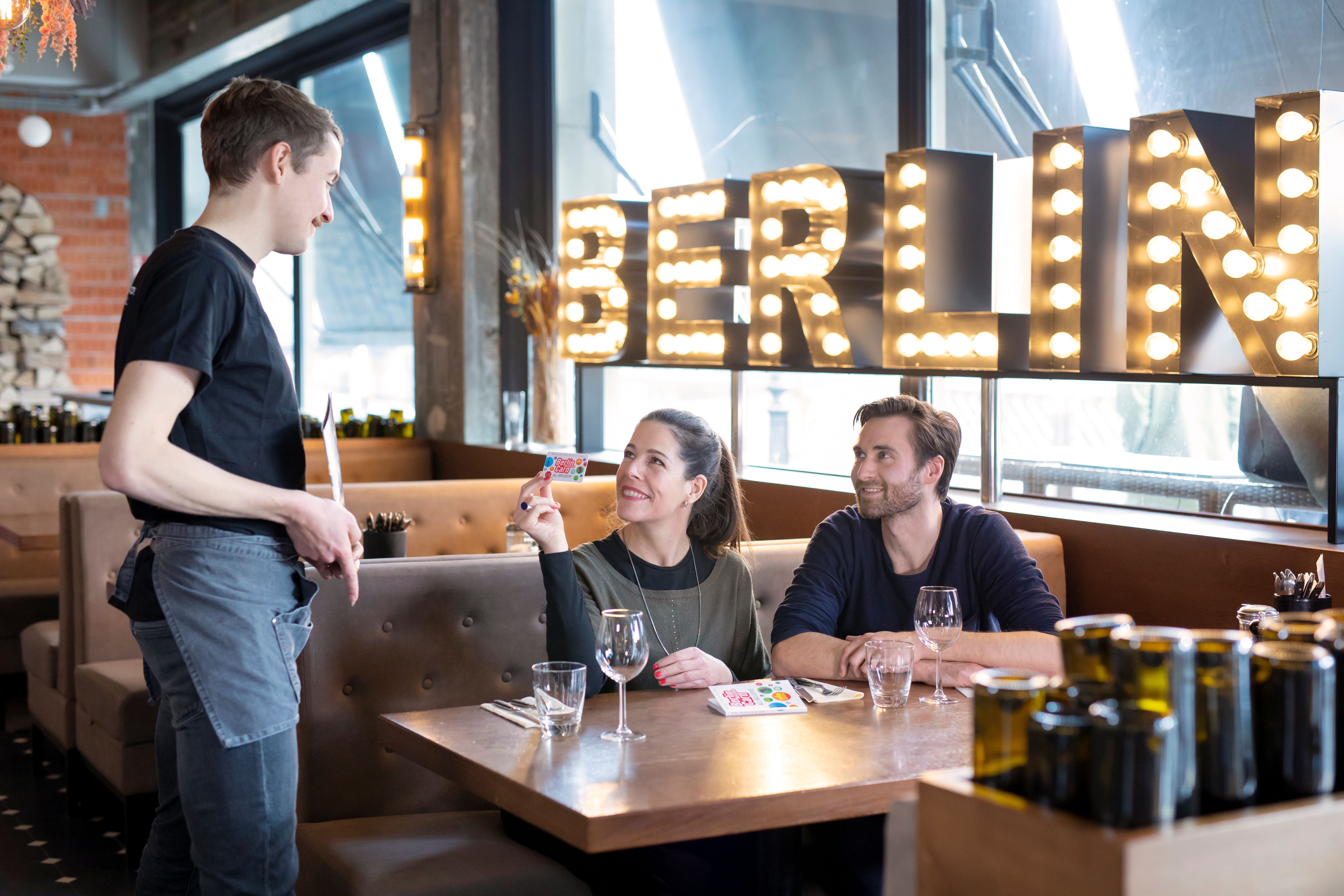 Paar sitzt in Restaurant und zeigt deren Berlin WelcomeCard einem Kellner