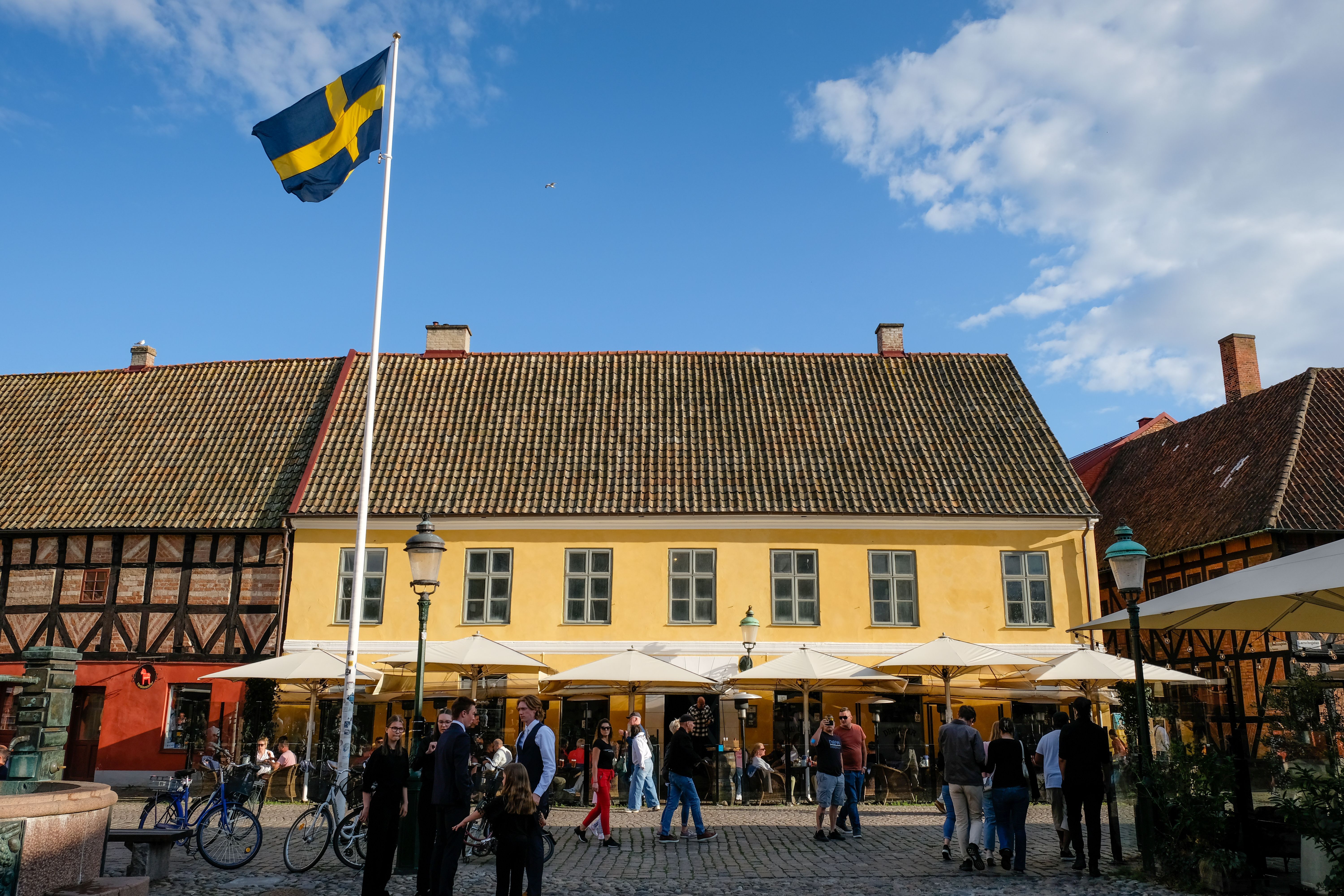 Historische Häuser in Malmö mit wehender Fahne und Menschen auf der Straße