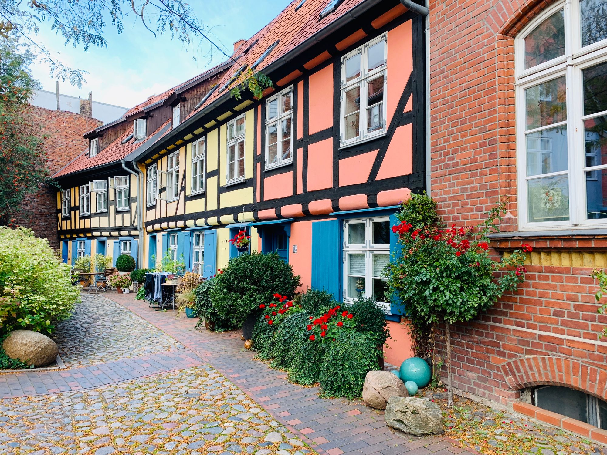 Traditionelle Fachwerkhäuser in einer Reihe, geschmückt mit Blumen vor den Haustüren und Fenstern.