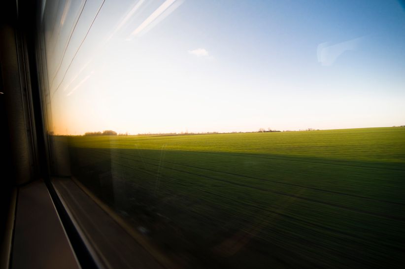 Blick aus dem ICE-Fenster auf grüne Felder