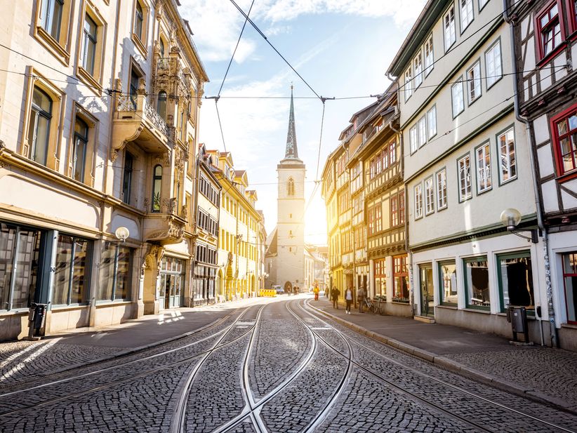 Erfurter Altstadtgasse mit Kopfsteinpflaster, beleuchtet von warmem Sonnenlicht zwischen historischen Gebäuden.