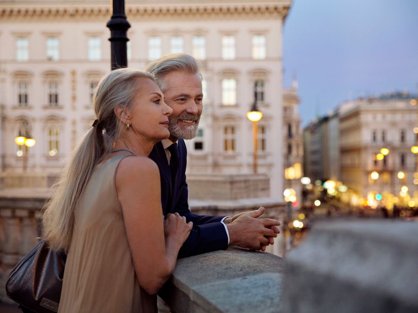 Paar lehnt an Balustrade und blickt über die Stadt am Abend