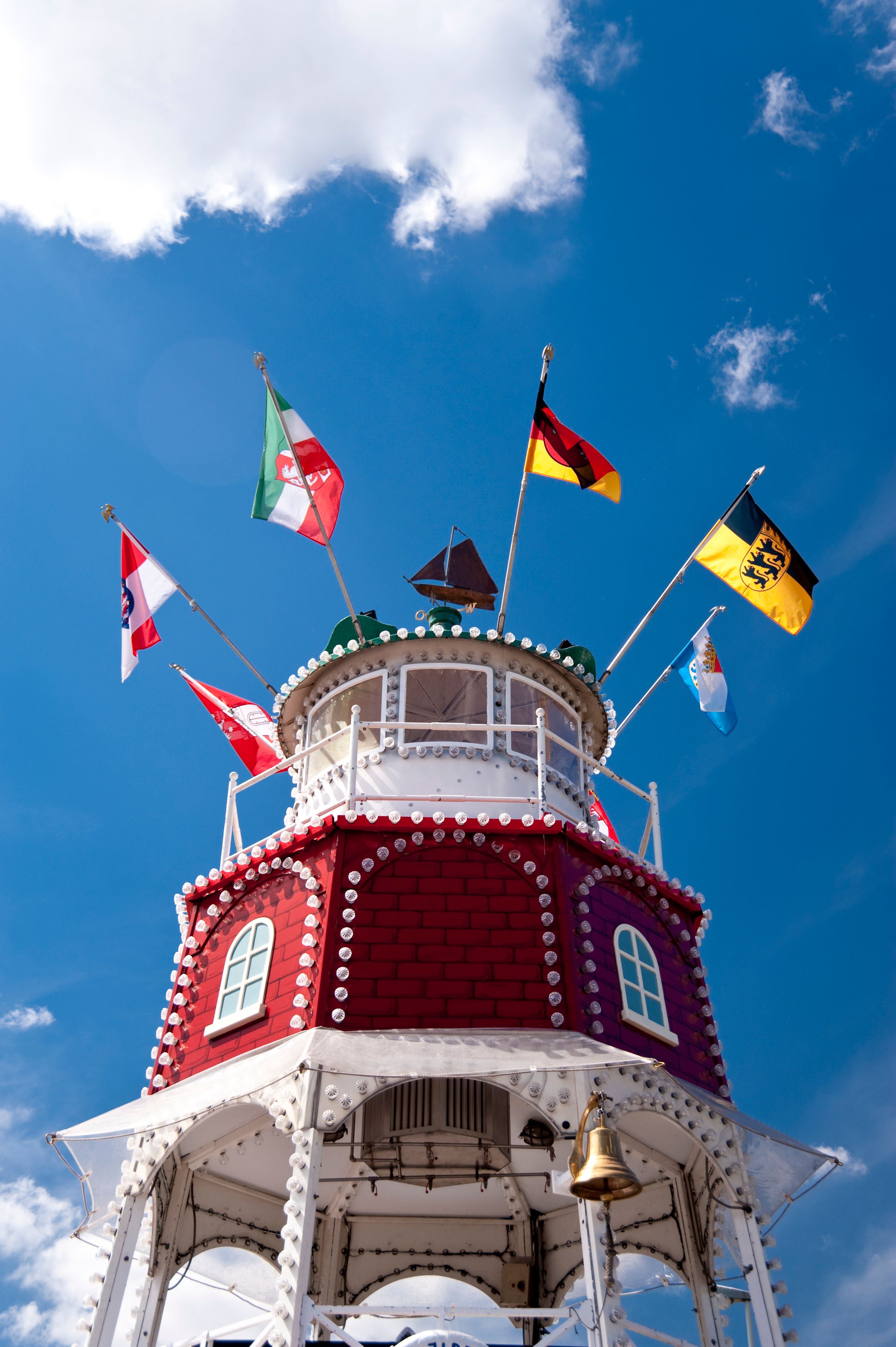 Der Rathausturm in Kiel festlich geschmückt mit bunten Fahnen anlässlich der Kieler Woche, vor blauem Himmel.
