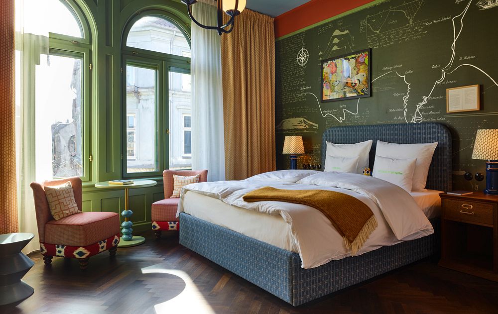 Hotelzimmer im 25hours IndreBy mit warmen Farben, grün orangenen Wänden und zwei Sesseln