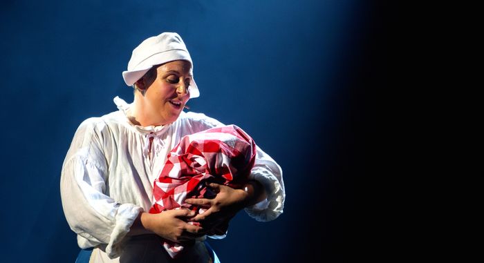 Darstellerin in der Rolle der Amme singt mit einem Bündel im Arm im Musical Die Amme
