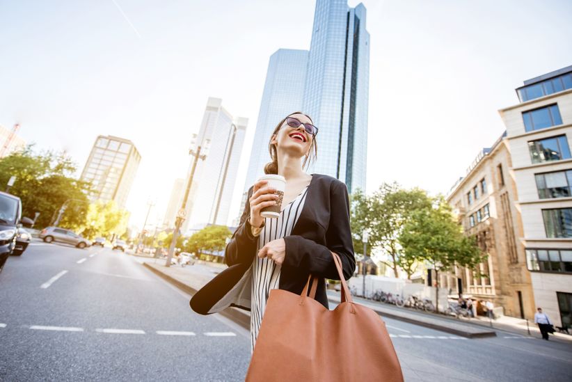 Geschäftsfrau auf einer Straße in Frankfurt mit Hochhaus im Hintergrund
