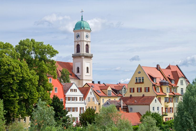 Panoramablick aus der Entfernung auf die Altstadt von Regensburg mit markanten Kirchtürmen, historischen Gebäuden und der Donau im Vordergrund.