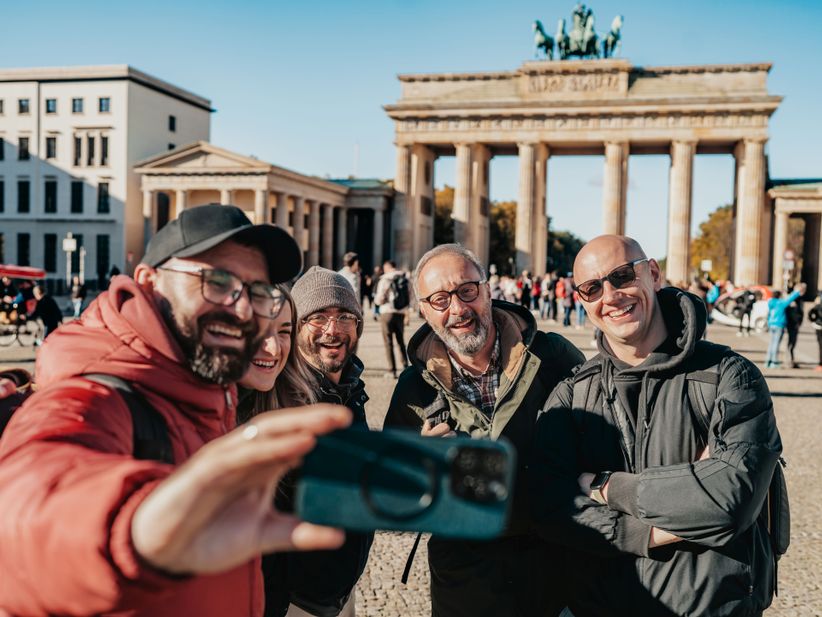 Reisegruppe schießt vor dem Brandenburger Tor in Berlin ein Selfie