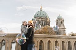Junges Paar umarmt sich und schaut Seifenblasen in Berlin an