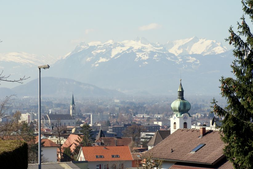 Im Vordergrund Dächer von Dornbirn und im Hintergrund Berge, die zum Teil mit Schnee bedeckt sind